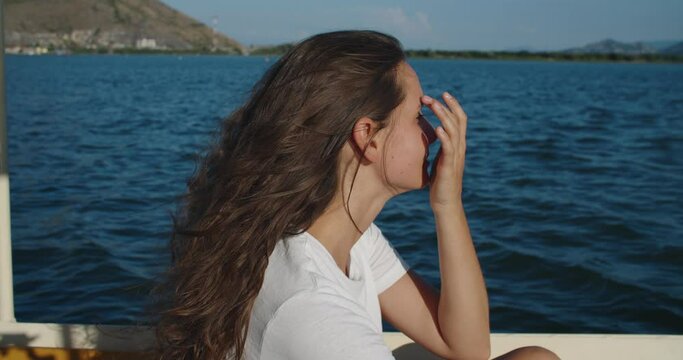 Happy woman with curly hair floats on a boat on the river. Her hair blows in the wind. Female portrait. High quality 4k footage
