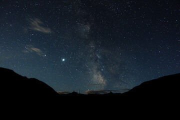 Starry sky and milky way in the mountains. Mountain village against the background of the night...