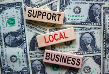 Concept text 'support local business' on wooden blocks on a beautiful background from dollar bills....