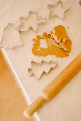 The process of making gingerbread cookies - rolling pin, molds and dough on a white table.