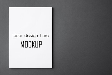 Paper sheet with text Mockup Your Design Here on dark grey background, top view