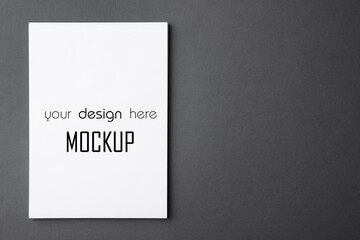 Paper sheet with text Mockup Your Design Here on dark grey background, top view
