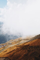 Cloudy day in mountains, clouds descend from the mountains to the village from above. descent by cable car