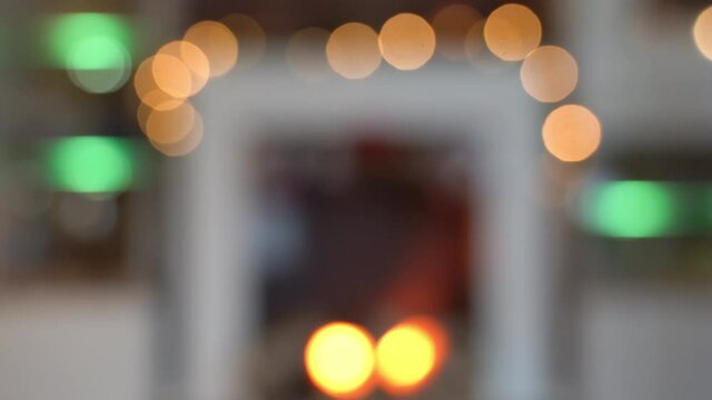 Bokeh of a fireplace with a chain of lights. In the fireplace a fire is glowing. The festive Christmassy living room is blurred. Background for christmassy montages.