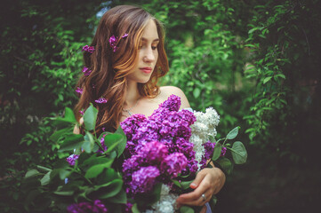 A young woman is holding a beautiful bouquet of lilacs.The girl's hair is loose.Flowers in your hair.