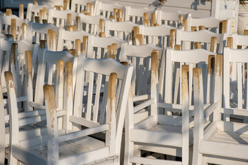 Close up of a bunch of white chairs upside down