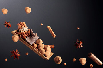 Falling old wooden dish with chocolates, cinnamon, coffee beans, and anise.