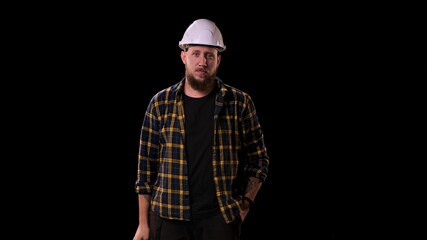 Foreman engineer puts on white helmet and looks at the camera. A real boss, man in plaid shirt, looks at his workers very seriously.
