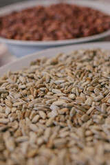 Roasted sunflower seeds in a plate in the foreground and peanuts in the background. Close-up.Macro shot. Selective focus.