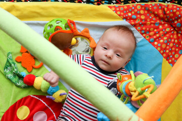 happy baby child infant playing with toys on the play mat