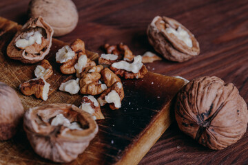 Walnut kernels and whole walnuts on rustic old wooden table.