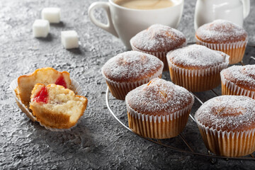 Coffee muffins on a wooden Board. Sweet muffins with berry filling on the table.Muffins sprinkled with powdered sugar.