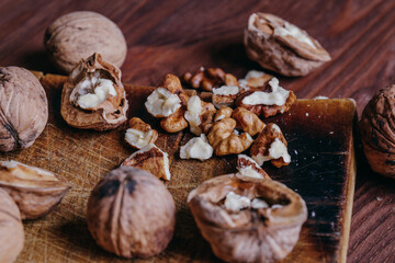 Walnut kernels and whole walnuts on rustic old wooden table.