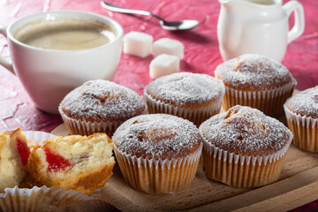 Coffee muffins on a wooden Board. Sweet muffins with berry filling on the table.Muffins sprinkled with powdered sugar.