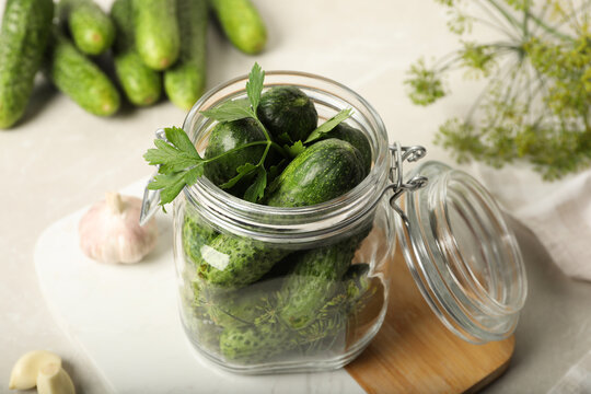 Pickling jar with fresh cucumbers on light table, closeup