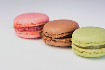 macro photo of green, red and brown macarons from the side against white background