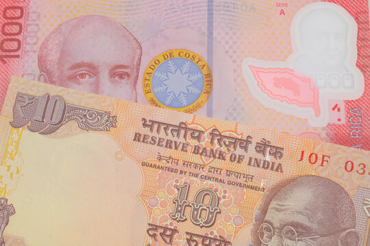 A Macro Image Of A Orange Ten Rupee Bill From India Paired Up With A Colorful Red One Thousand Colones Bank Note From Costa Rica.  Shot Close Up In Macro.