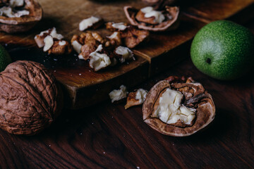 Walnut kernels, whole walnuts and green walnuts on rustic old wooden table.