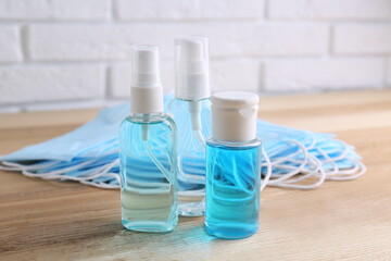 Hand sanitizers and respiratory masks on wooden table. Protective essentials during COVID-19 pandemic