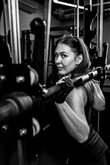 portrait of a girl exercising in a gym and squatting in a smitt machine.