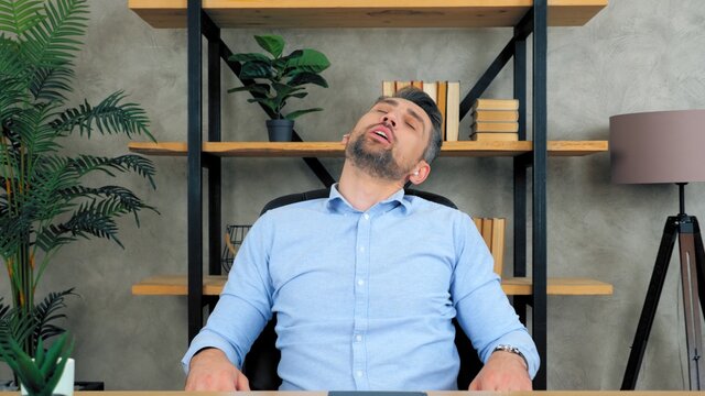 Tired Gray-haired Bearded Business Man Manager SEO Freelancer Wears Wireless Earphones Asleep On Chair At Table After Long Hard Work At Home Office