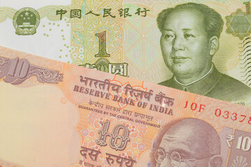 Fototapeta na wymiar A macro image of a orange ten rupee bill from India paired up with a green and white one yuan note from China. Shot close up in macro.