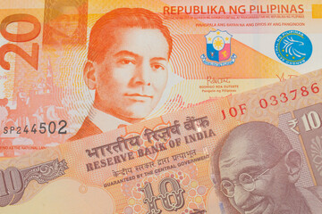 Fototapeta premium A macro image of a orange ten rupee bill from India paired up with a orange and white twenty piso note from the Philippines. Shot close up in macro.