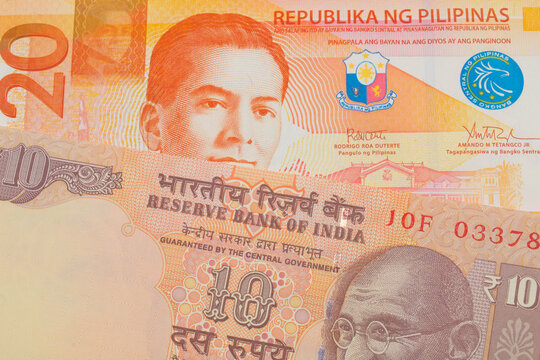A macro image of a orange ten rupee bill from India paired up with a orange and white twenty piso note from the Philippines.  Shot close up in macro.