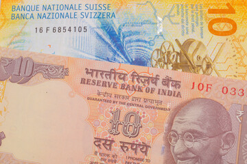 A macro image of a orange ten rupee bill from India paired up with a yellow Swiss ten franc bill.  Shot close up in macro.