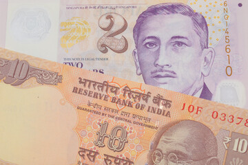 A macro image of a orange ten rupee bill from India paired up with a purple and white, plastic two dollar bill from Singapore.  Shot close up in macro.