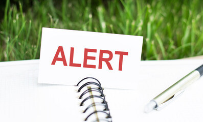 text alert on desktop on a white business card on a notepad and a pen. Business concept