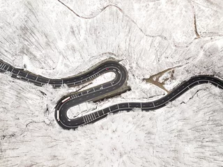 Foto op Aluminium Curvy windy road in snow covered forest, top down aerial view. © Rafaila Gheorghita