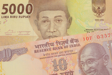 Fototapeta premium A macro image of a orange ten rupee bill from India paired up with a orange five thousand Indonesian rupiah note. Shot close up in macro.