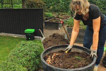 A woman putting down bokashi, food waste, effective microorganisms, in a pot in a garden.