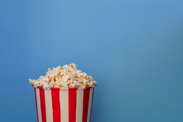 A bucket full of popcorn on a blue background