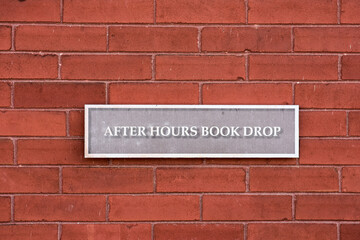 Obraz premium After hours book drop sign at a public library.