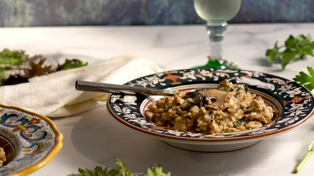 Extreme closeup slider to left Italian bowls of shiitake kale risotto with wine.