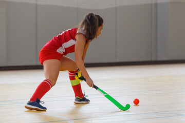 Young woman player in attack at indoor hockey match