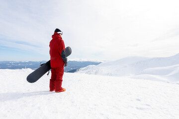 Fototapeta na wymiar winter, leisure, sport and people concept - Snowboarder stands on backcountry slope and holds snowboard. Ski concept