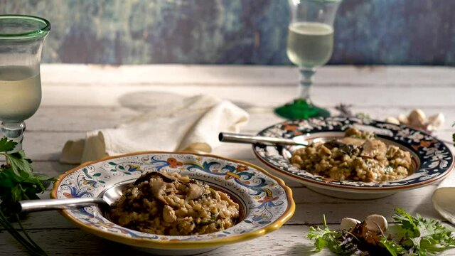 Slide to right closeup of Italian bowls mushroom kale risotto and white wine.