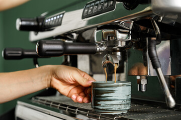 Woman coffee shop worker preparing coffee on professional coffee machine