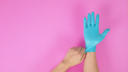 Right hand is wear and left hand is pull  latex glove on pink background.