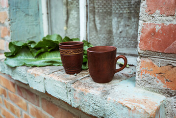 brown clay cups with green leaves on an old windowsill
