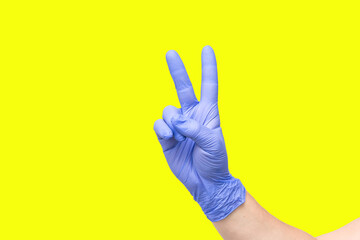 male hand on yellow background showing the symbol of victory or the number two or sexual insult