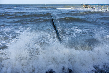 Breakwaters in the sea. Waves beat against breakwaters. Splashing sea waves.