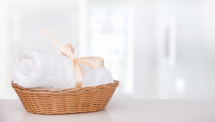 Fototapeta na wymiar Mossy white rolled up towel in wicker basket on table