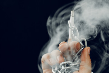 Male hand in metal chains holding cigarette