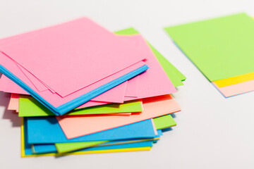 Stacks of paper of different colors are arranged in a column on a white surface.