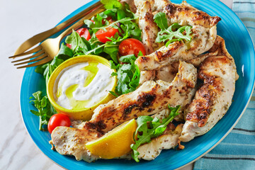 Grilled chicken with arugula salad on a blue plate