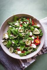 Green orecchiette with arugula tomato sauce and goat cheese on a green surface